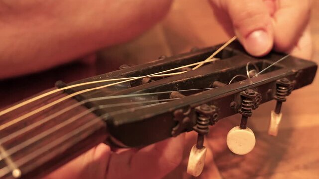 Musician changing strings on old classical guitar