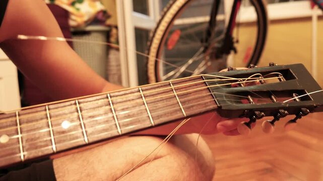 Musician changing strings on a classic acoustic guitar at home