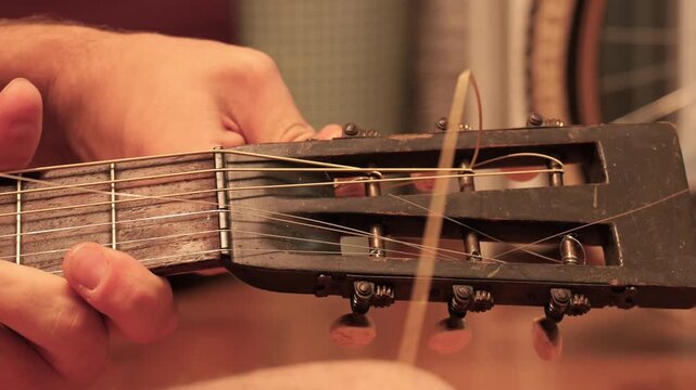 Musician changing broken string on acoustic guitar