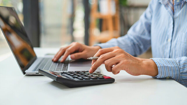 Professional Accountant Using Calculator and Laptop to Manage Financial Data for Business Budgeting and Corporate Reporting