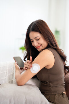 a woman with A Continuous Glucose Monitor (CGM) wearable device  tracks  interstitial fluid glucose levels 24 hours a day.
