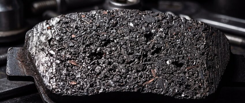 Worn car brake pad with rough metallic friction surface texture macro shot showcasing industrial automotive parts and vehicle maintenance service