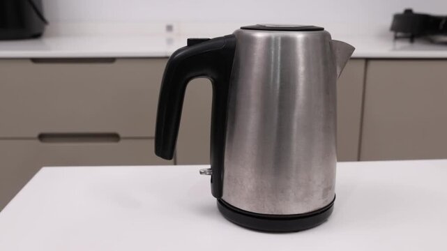 Stainless steel electric kettle boiling water and automatically turning off with indicator light off.