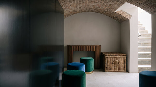 Velvet stools and a wicker trunk fill a vaulted brick cellar