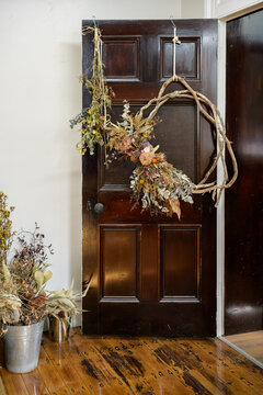 Decorative dried flower wreath hanging on a wooden door in a cozy interior setting - vertical