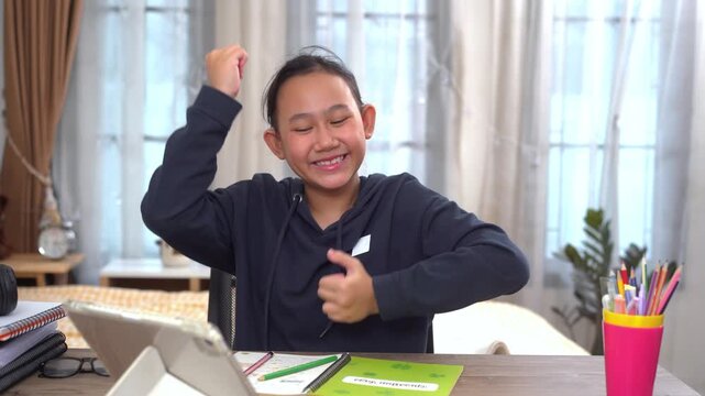 Young girl smiled happily and raised her arms in delight after answering the question correctly during her online lesson