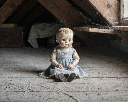 Cracked Antique Doll Sitting Alone in Dusty Attic