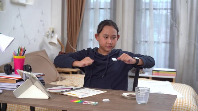 Young girl is taking a break from her online classes at home and stretching tired body