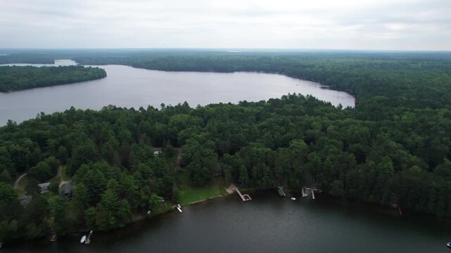 Right to left Aerial of Eagle River Wisconsin Northwoods in the summer time.  Tall pines and the chain of lakes.