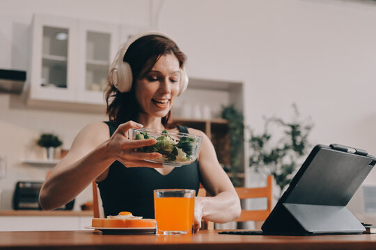 Woman preparing green smoothie in bright kitchen with fresh fruits and vegetables, healthy eating lifestyle moment in natural daylight