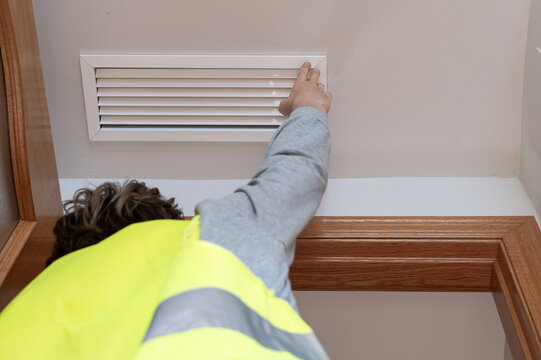 Professional wearing a reflective vest inspecting a ceiling air vent, checking the home's ventilation and hvac system during a thorough property assessment