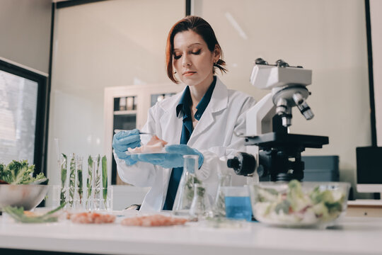 Scientists in lab coats work with plants in a modern lab, focusing on research and experimentation under bright, sterile conditions.