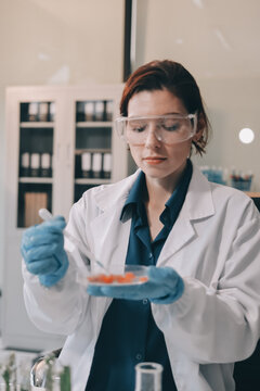 Scientists in lab coats work with plants in a modern lab, focusing on research and experimentation under bright, sterile conditions.