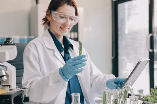 Scientists in lab coats work with plants in a modern lab, focusing on research and experimentation under bright, sterile conditions.