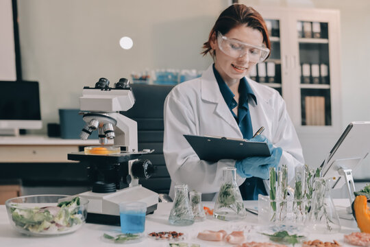 Scientists in lab coats work with plants in a modern lab, focusing on research and experimentation under bright, sterile conditions.
