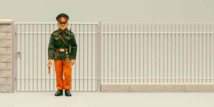 A uniformed guard stands attentively at a gate. The guard wears a green jacket and orange pants, with a cap on their head. The gate is tall and white, with vertical bars.