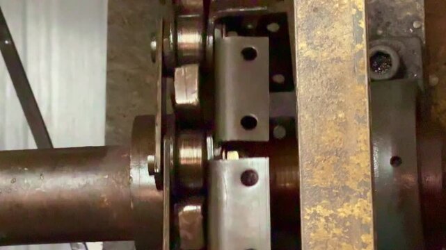 Industrial chain drive rotating on gear system, close-up view. Mechanical, manufacturing, and factory machinery concept footage.