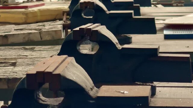 Industrial workshop with a row of heavy-duty bench vises aligned on workbenches. Close-up view of metalworking equipment in a manufacturing and fabrication environment.
