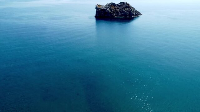Drone footage showcasing the crystal-clear turquoise waters, rocky reefs and tranquil coastline of Skala Eressos Beach on Lesvos Island, Greece, on a sunny summer day.