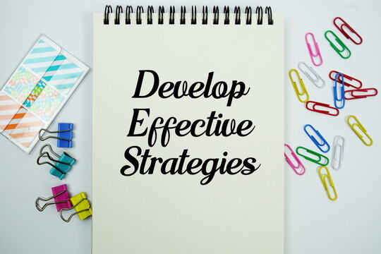 Develop Effective Strategies text message written on notepad with stationery flat lay on white background
