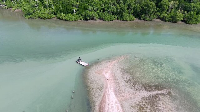 Aerial view of a tranquil river bend. Crystal clear water flows around a sandy beach at Pulau Aman