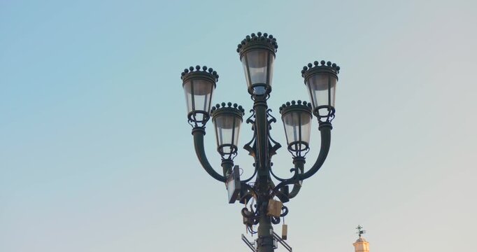 Ornate multi-headed street lamp rises into a pale evening sky in Turin, shown with a slow upward tilt.