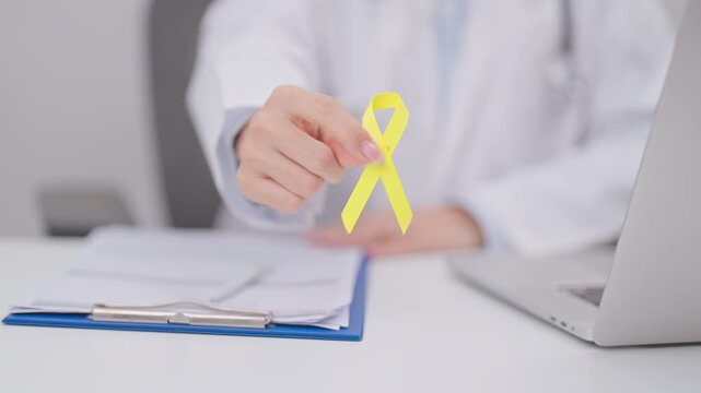 Doctor with Gold Yellow Ribbon for concept of September Childhood cancer Awareness month, July Sarcoma, bone and bladder cancer, support survivor. Healthcare and World Cancer day
