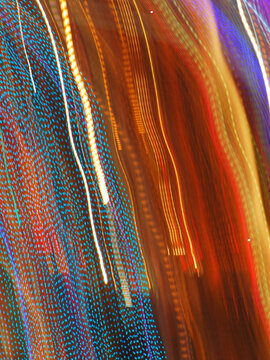 Pulsating trails of light from the carousel, moving in the darkness, almost vertically, from top to bottom.
