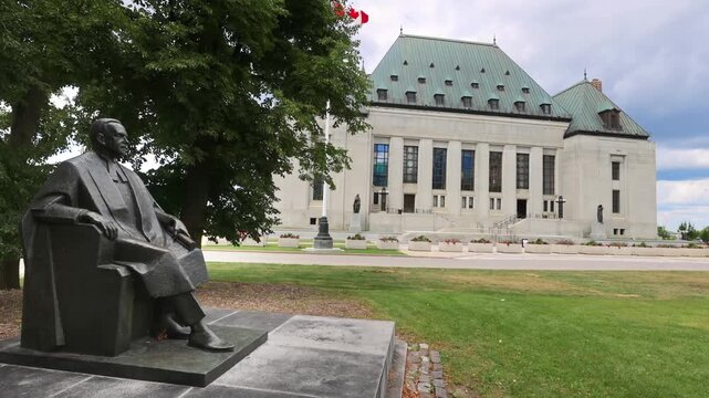 Bronze statue of Louis St. Laurent in front of Supreme Court building in wide low angle view in Ottawa, Ontario, Canada. 