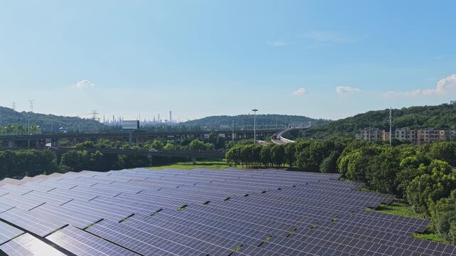 Aerial view moving across solar panels beside trees and roads