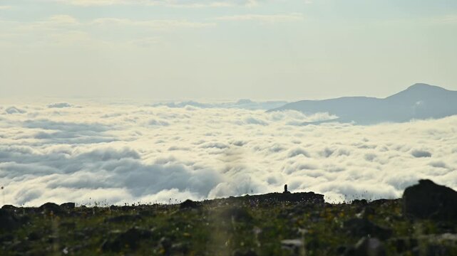 Scenic view of clouds rolling over mountains with rocky foreground elements