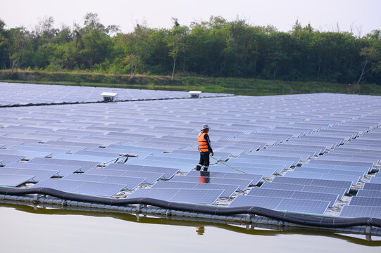 Workers are cleaning solar panels in a large body of water, a clean energy source for electricity generation.
