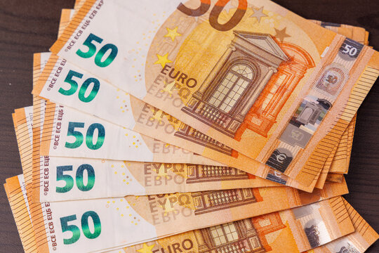 Fifty euro banknotes in a fan shape on a dark wooden table, overhead top view showing wealth, business finance, and savings