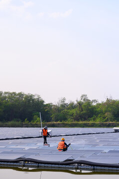 Workers are cleaning solar panels in a large body of water, a clean energy source for electricity generation.