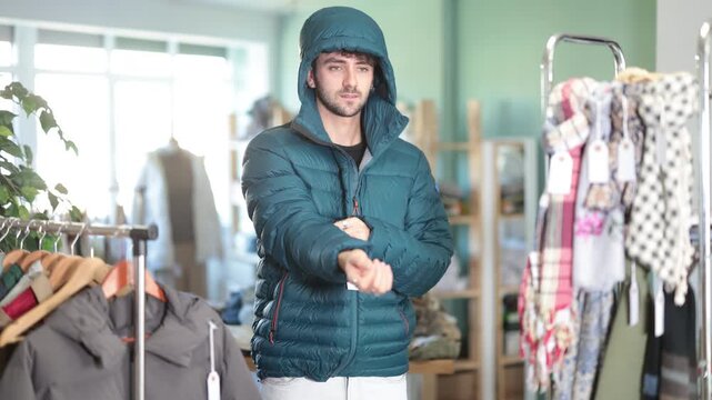 Young man tries on down jacket in a clothing store. High quality 4k footage