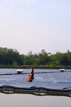 Workers are cleaning solar panels in a large body of water, a clean energy source for electricity generation.