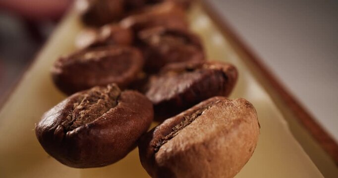 Macro tracking shot of roasted coffee beans on conveyor belt in production, macro probe lens.