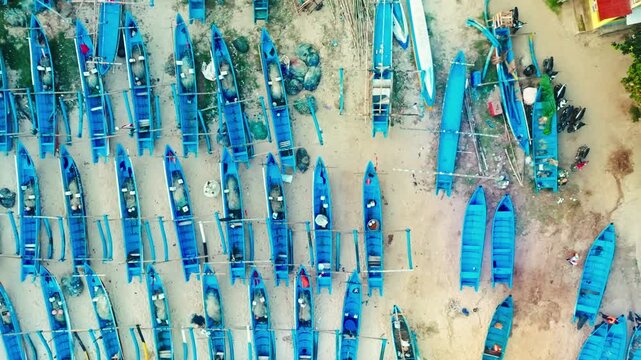 Top-down aerial view reveals orderly rows of colorful fishing boats arranged across the sandy shoreline at Ngerenean Beach.