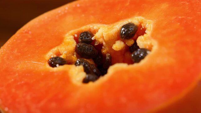 Close-up of ripe papaya flesh and glossy black seeds, showcasing the vibrant orange color and natural texture of this tropical fruit. Rich in vitamins, antioxidants, and dietary fiber, the image is id