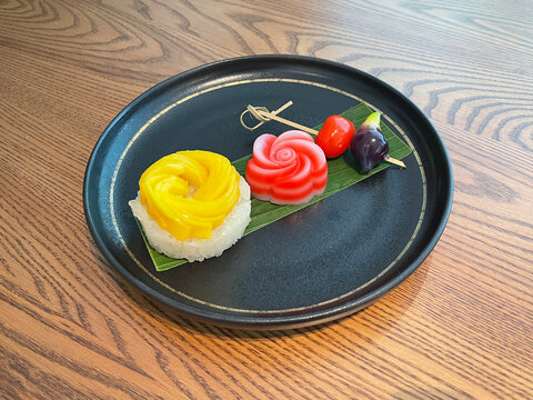 Thai Dessert Platter. A delightful assortment featuring sweet mango sticky rice, chewy layered jelly (Khanom Chan), and glossy, mung bean marzipan fruits (Luk Chup)