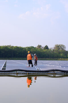 Workers are cleaning solar panels in a large body of water, a clean energy source for electricity generation.