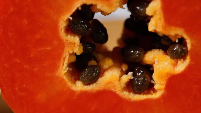 Close-up of ripe papaya flesh and glossy black seeds, showcasing the vibrant orange color and natural texture of this tropical fruit. Rich in vitamins, antioxidants, and dietary fiber, the image is id