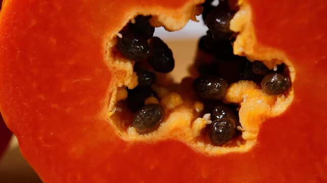 Close-up of ripe papaya flesh and glossy black seeds, showcasing the vibrant orange color and natural texture of this tropical fruit. Rich in vitamins, antioxidants, and dietary fiber, the image is id