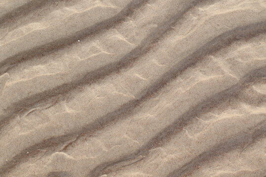 textured beige sand waves under the clear water