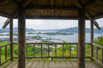 Fototapeta premium Scenic landscape view of the Seto Inland Sea framed through a wooden gazebo or observation deck with pillars and railing