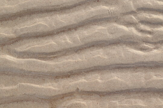 textured beige sand waves under the clear water