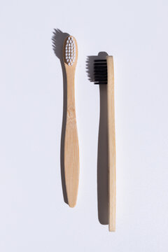 two bamboo toothbrushes isolated on white background, front and side views with white and black bristles, sustainable oral care concept, natural eco friendly dental products with copy space
