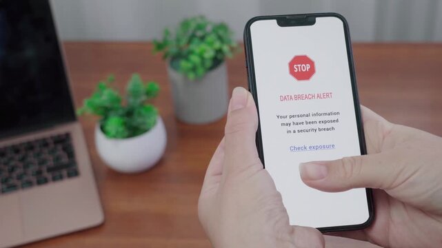 Stop sign data breach AI notice appears on a phone as a thumb nears the Check exposure link on a tidy desk.
