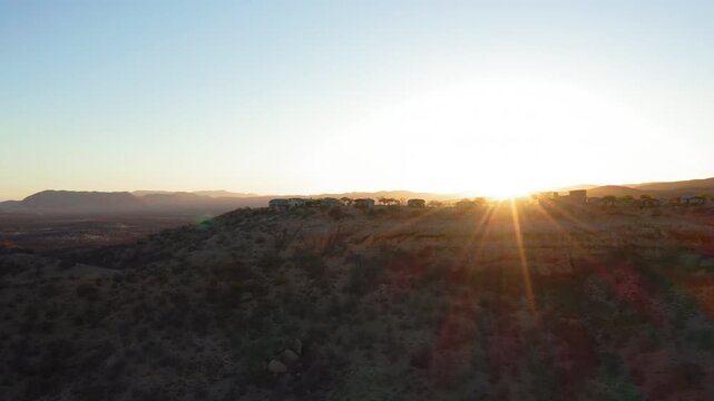 Slow panoramic drone pan of silhouetted luxury lodge, Ugab Valley, Namibia at sunset. Clear cloudless sky.