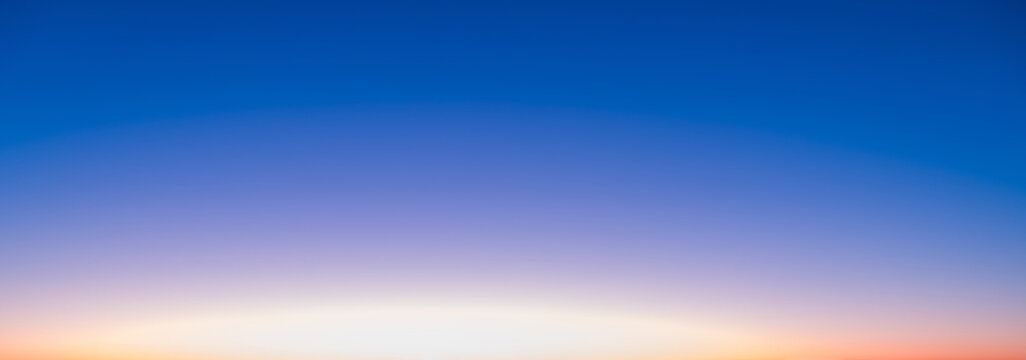 The transitional colors of the sky at sunrise. The sun is rising against a blue sky.